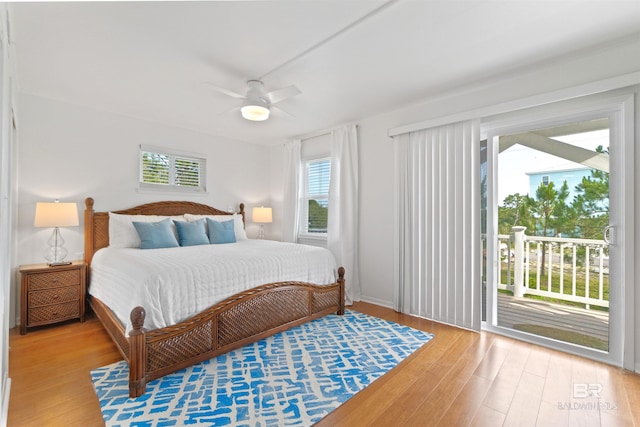 bedroom featuring access to exterior, a ceiling fan, multiple windows, and wood finished floors