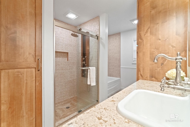 bathroom with a stall shower, a tub, and vanity