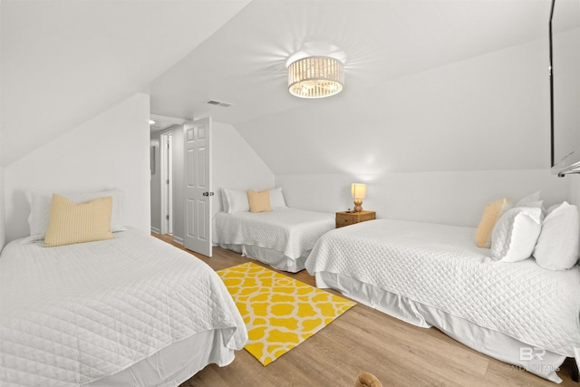 bedroom featuring lofted ceiling, wood finished floors, and visible vents