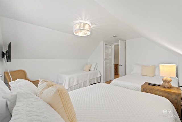 bedroom featuring visible vents, vaulted ceiling, and a closet