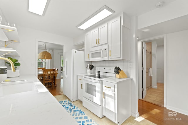 kitchen featuring pendant lighting, backsplash, white cabinets, light wood-type flooring, and white appliances