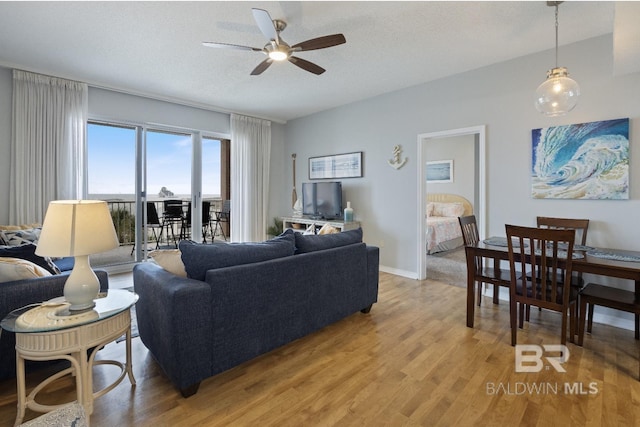 living room with ceiling fan, light hardwood / wood-style flooring, and a textured ceiling