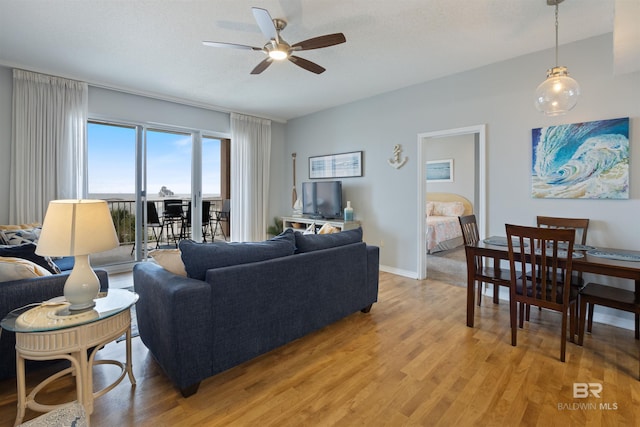 living room with ceiling fan, a textured ceiling, and light wood-type flooring