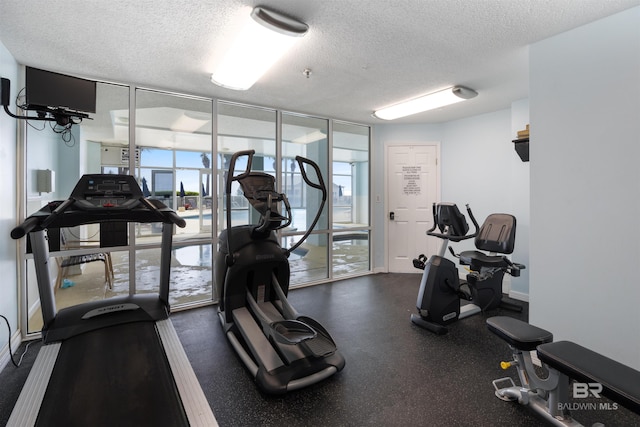 gym featuring a textured ceiling and a wall of windows