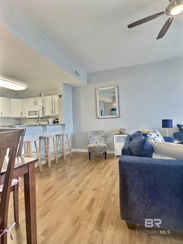 living room with ceiling fan and light hardwood / wood-style floors