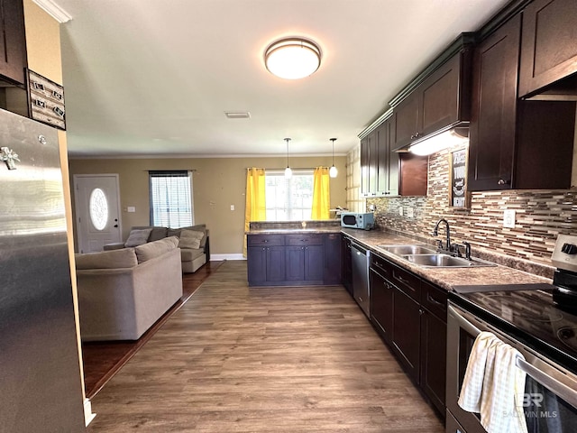 kitchen with dark brown cabinetry, appliances with stainless steel finishes, ornamental molding, a sink, and open floor plan