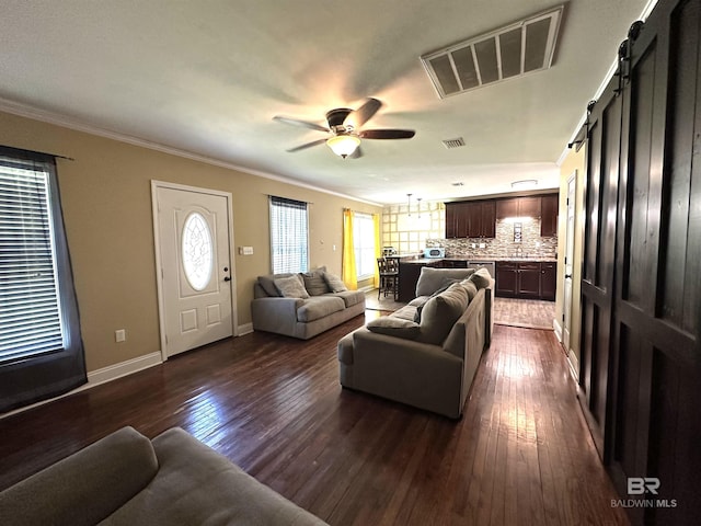 living room with a barn door, visible vents, a healthy amount of sunlight, and dark wood-type flooring