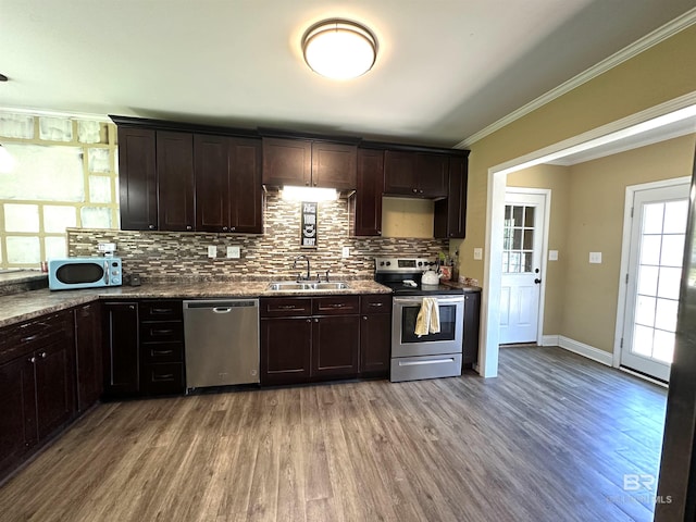 kitchen featuring wood finished floors, decorative backsplash, appliances with stainless steel finishes, dark brown cabinets, and a sink
