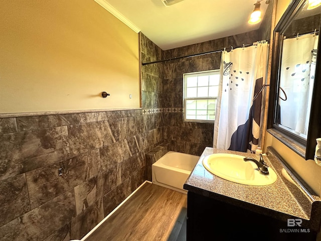bathroom with wood finished floors, tile walls, a wainscoted wall, vanity, and shower / tub combo with curtain