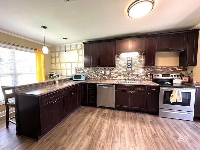 kitchen featuring stainless steel appliances, light wood-style floors, ornamental molding, a sink, and a peninsula