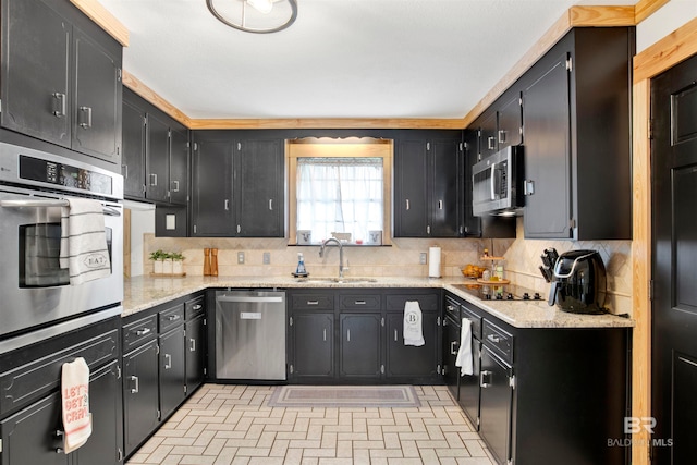 kitchen featuring light stone countertops, decorative backsplash, sink, and stainless steel appliances