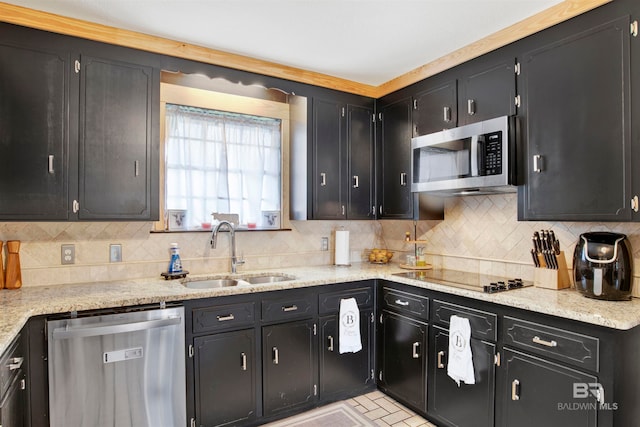 kitchen with appliances with stainless steel finishes, backsplash, light stone counters, and sink