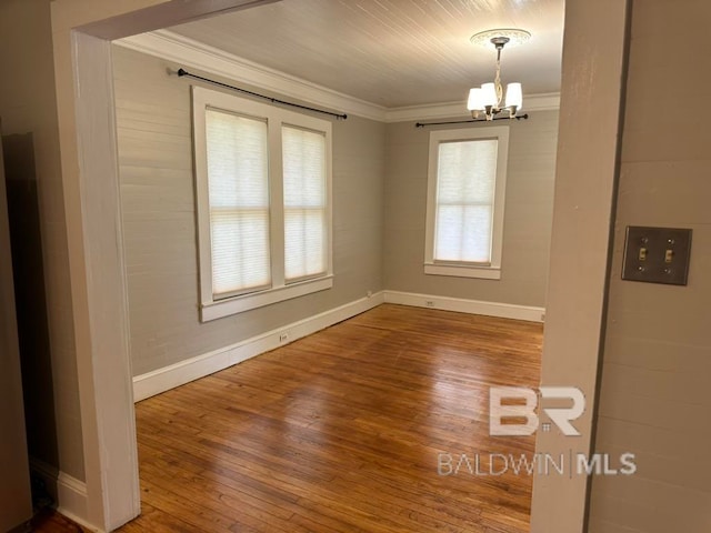 unfurnished dining area with a chandelier, hardwood / wood-style flooring, and crown molding