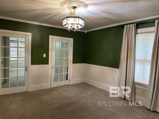 empty room with a chandelier, carpet flooring, and crown molding