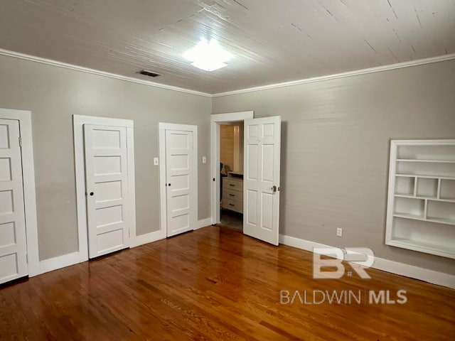 unfurnished bedroom featuring multiple closets, dark wood-type flooring, and crown molding