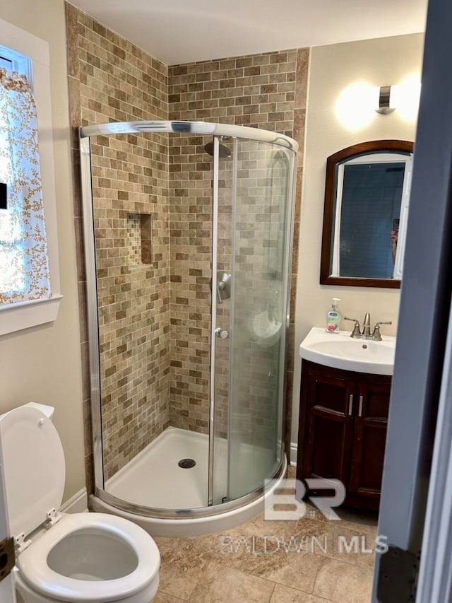 bathroom with vanity, tile patterned floors, toilet, and a shower with door