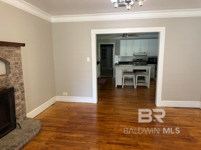 unfurnished living room with a brick fireplace, dark hardwood / wood-style flooring, ceiling fan, and crown molding