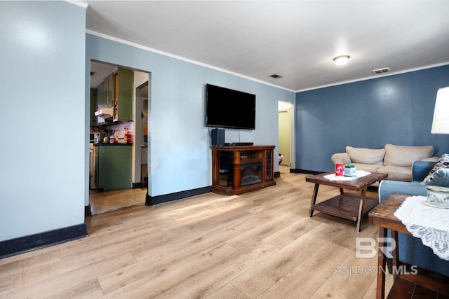 living room with crown molding and light hardwood / wood-style flooring