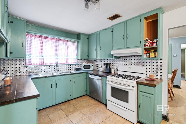 kitchen with tasteful backsplash, sink, green cabinets, light tile patterned floors, and white appliances