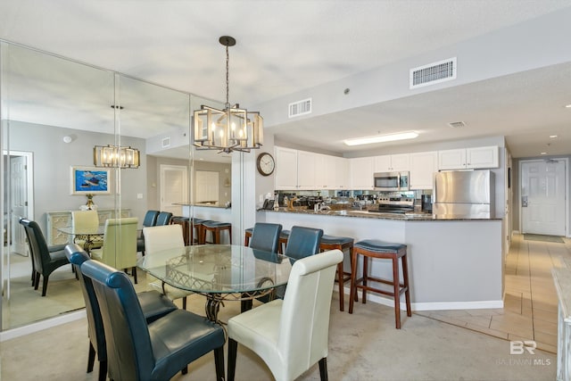 dining space featuring a notable chandelier, light tile patterned floors, and a textured ceiling