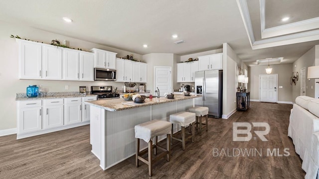 kitchen with white cabinets, stainless steel appliances, dark wood finished floors, and a kitchen breakfast bar