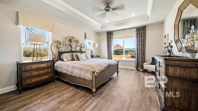 bedroom with baseboards, ceiling fan, ornamental molding, wood finished floors, and a tray ceiling