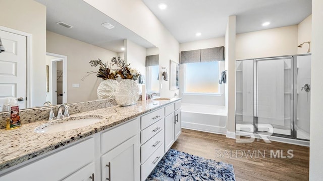 full bathroom featuring a stall shower, visible vents, a sink, and wood finished floors