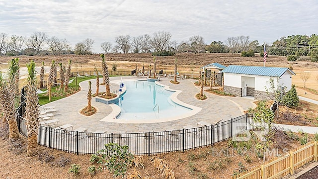 community pool featuring a rural view, fence, an outdoor structure, and a patio