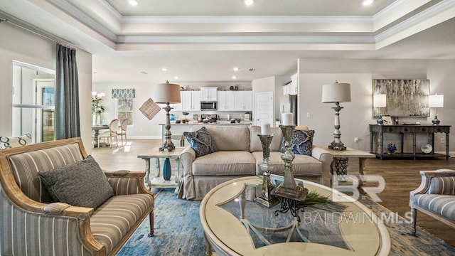 living room with ornamental molding, a raised ceiling, and wood finished floors