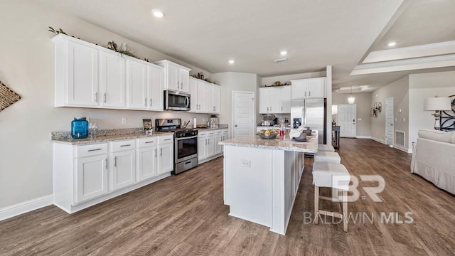 kitchen featuring stainless steel appliances, wood finished floors, visible vents, and white cabinets