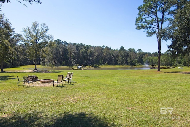 view of property's community with a yard, a water view, and a fire pit