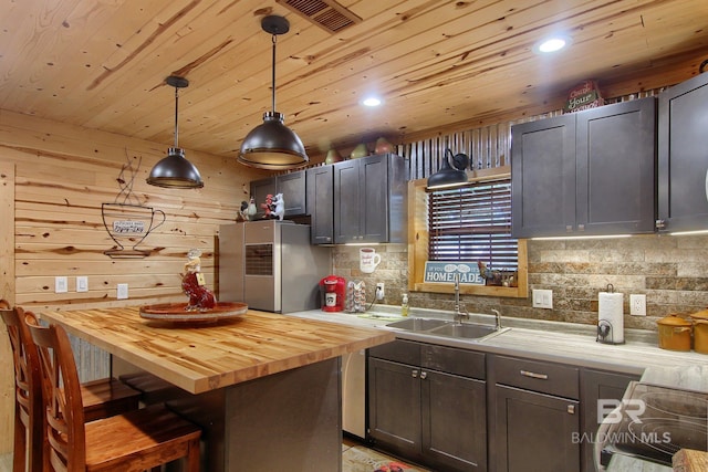 kitchen with stainless steel refrigerator with ice dispenser, hanging light fixtures, wood counters, a center island, and range