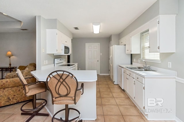 kitchen with a breakfast bar, white cabinetry, sink, and white appliances