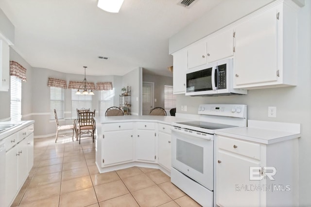 kitchen with kitchen peninsula, white appliances, light tile patterned floors, white cabinets, and hanging light fixtures