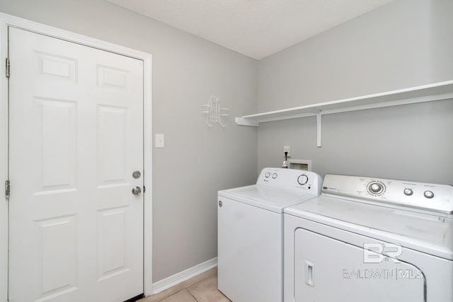 clothes washing area featuring washer and dryer, light tile patterned floors, and a textured ceiling