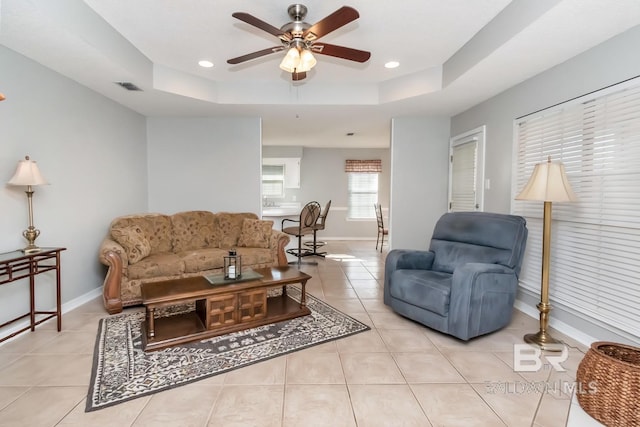 tiled living room featuring a raised ceiling and ceiling fan