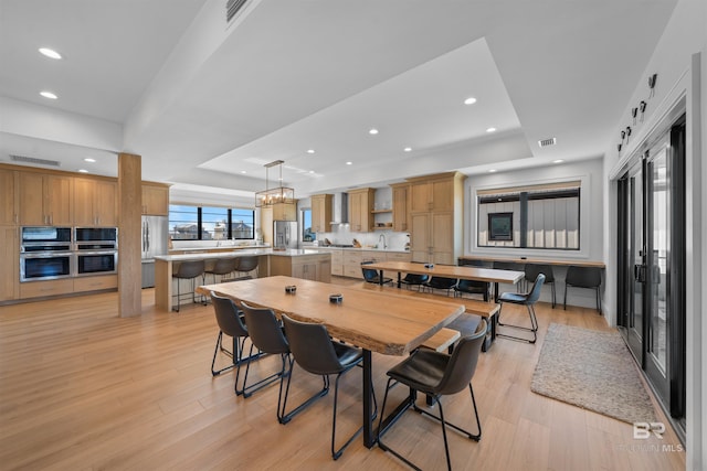 dining space with a tray ceiling, visible vents, recessed lighting, and light wood-type flooring