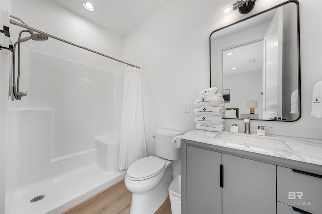 bathroom with toilet, vanity, wood finished floors, and a shower stall