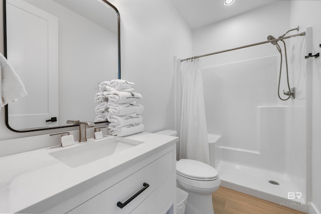 bathroom featuring toilet, a stall shower, vanity, and wood finished floors
