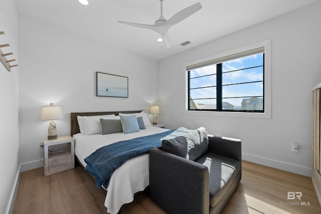 bedroom with baseboards, visible vents, and wood finished floors
