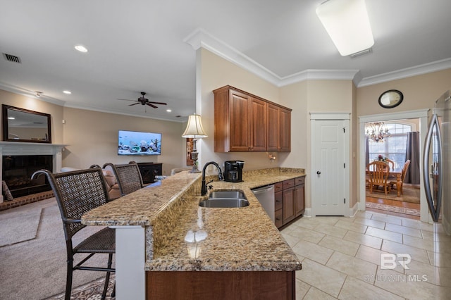 kitchen featuring stainless steel appliances, a peninsula, a sink, a brick fireplace, and crown molding