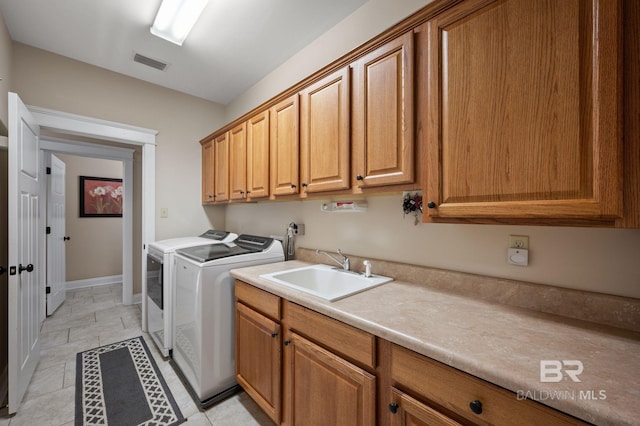 laundry room featuring cabinet space, visible vents, baseboards, washing machine and dryer, and a sink