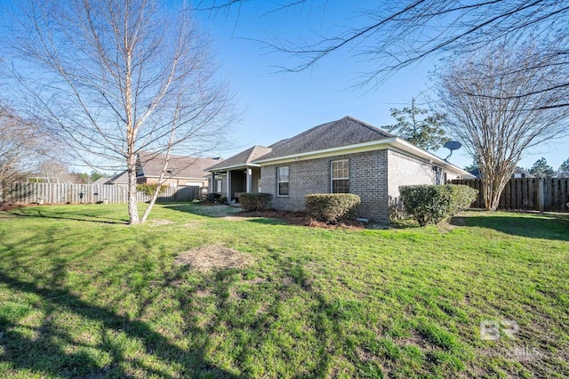 view of home's exterior with brick siding, fence, and a lawn