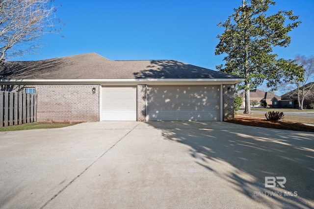 exterior space with a garage, driveway, brick siding, and fence