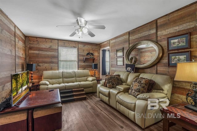 living room with dark hardwood / wood-style floors, ceiling fan, and wood walls