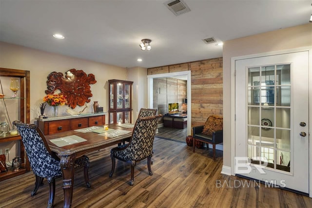 dining space featuring dark wood-type flooring and wood walls