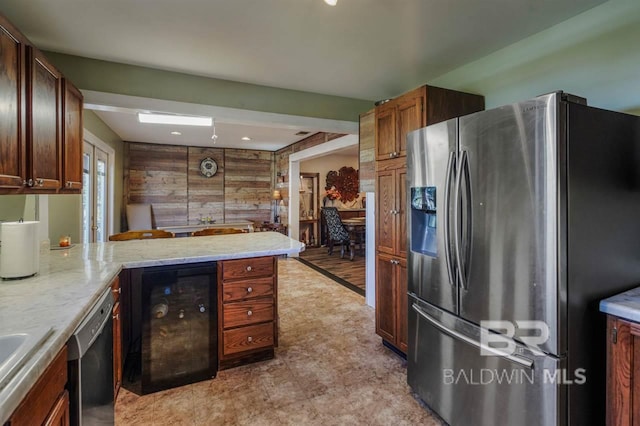 kitchen with appliances with stainless steel finishes, wooden walls, wine cooler, light stone countertops, and kitchen peninsula