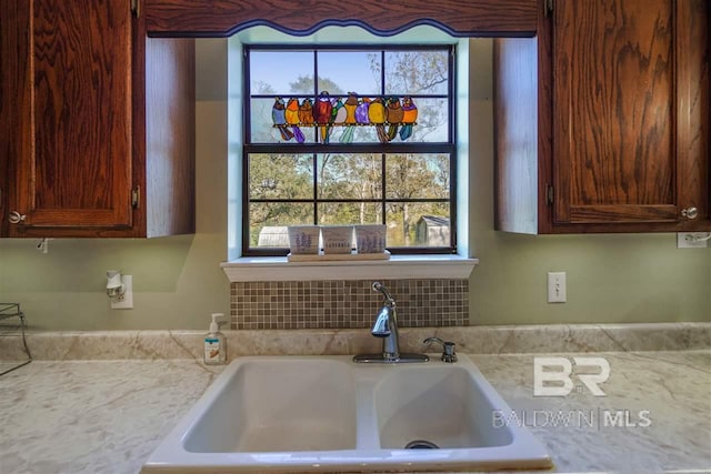 kitchen featuring light stone counters and sink