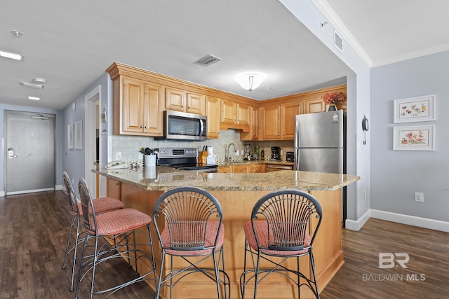 kitchen featuring appliances with stainless steel finishes, light stone counters, dark hardwood / wood-style floors, and ornamental molding