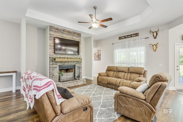 living room featuring ceiling fan, a fireplace, a healthy amount of sunlight, and a tray ceiling